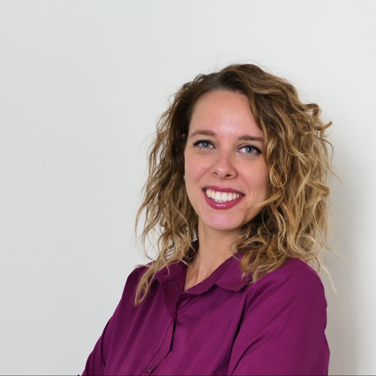 Ritratto della Dott.ssa Federica Tuzza, psicologa e psicoterapeuta, con un sorriso accogliente e un'espressione professionale. Indossa un abito color prugna e ha le braccia incrociate in un gesto di sicurezza e apertura. Lo sfondo chiaro mette in risalto la sua figura, trasmettendo un senso di fiducia, empatia e professionalità.